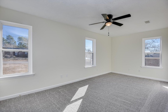 unfurnished room with carpet flooring, a healthy amount of sunlight, visible vents, and baseboards