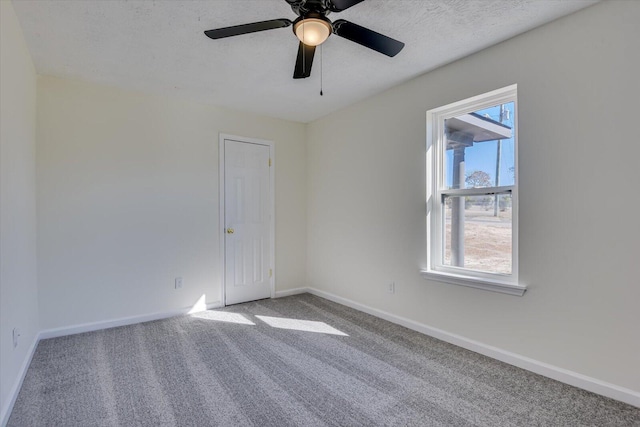 empty room with a textured ceiling, carpet floors, and baseboards