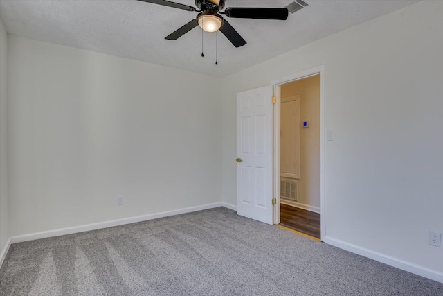 carpeted empty room featuring baseboards, a textured ceiling, visible vents, and a ceiling fan