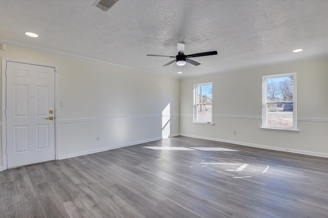 spare room with a textured ceiling, wood finished floors, visible vents, and baseboards