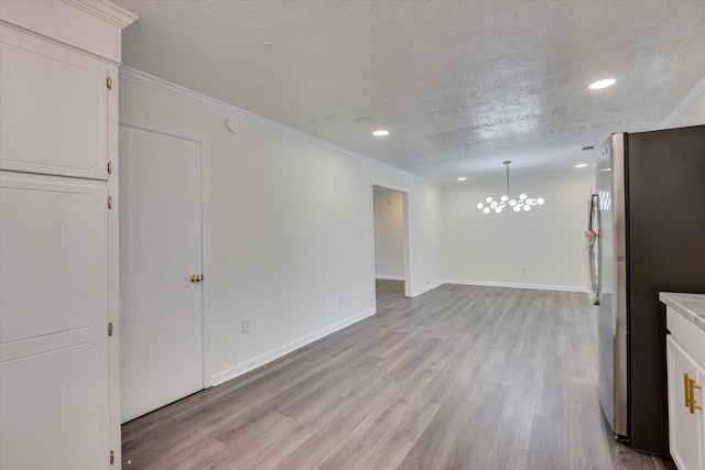 kitchen featuring light wood-type flooring, baseboards, a textured ceiling, and freestanding refrigerator