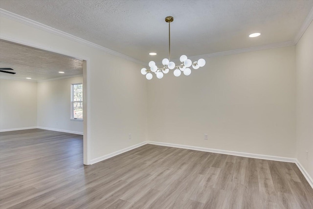 spare room featuring a textured ceiling, wood finished floors, baseboards, ornamental molding, and an inviting chandelier