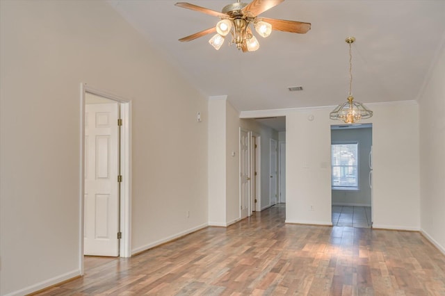 spare room with crown molding, wood finished floors, visible vents, and baseboards