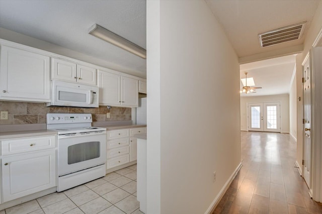 kitchen featuring light countertops, visible vents, decorative backsplash, white cabinets, and white appliances