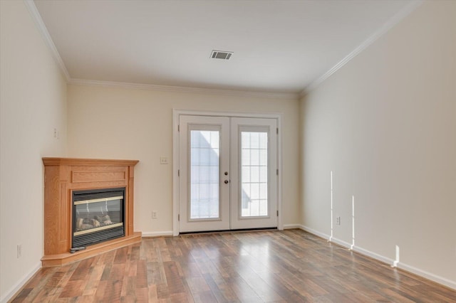 doorway to outside with visible vents, a glass covered fireplace, ornamental molding, wood finished floors, and french doors