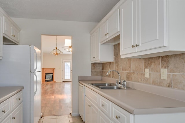 kitchen with light countertops, white appliances, a sink, and white cabinets