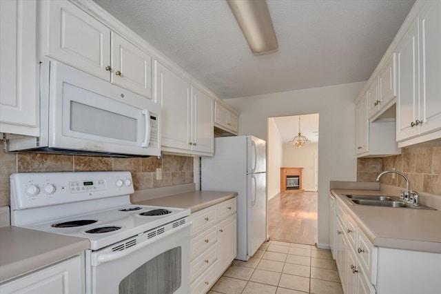 kitchen with light countertops, white appliances, a sink, and white cabinetry