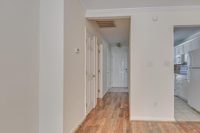 hall featuring baseboards, ornamental molding, visible vents, and light wood-style floors