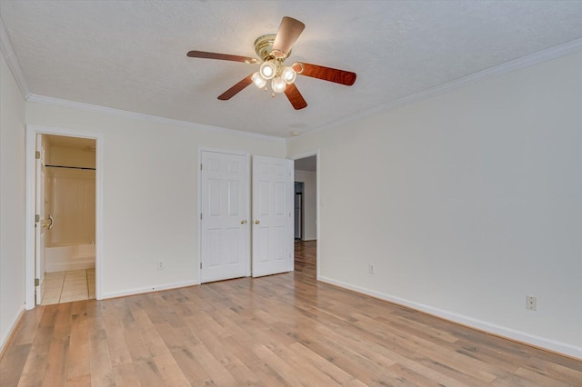 unfurnished bedroom featuring light wood finished floors, baseboards, ensuite bathroom, a textured ceiling, and crown molding