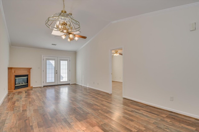 unfurnished living room with lofted ceiling, ceiling fan with notable chandelier, wood finished floors, french doors, and crown molding