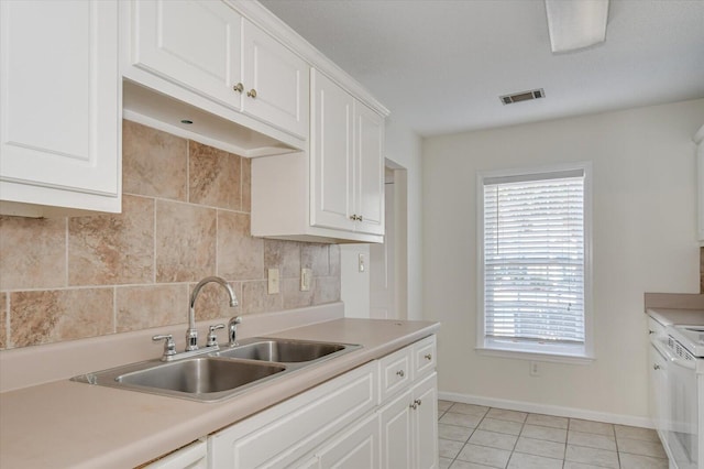 kitchen featuring a sink, visible vents, white cabinetry, light countertops, and tasteful backsplash