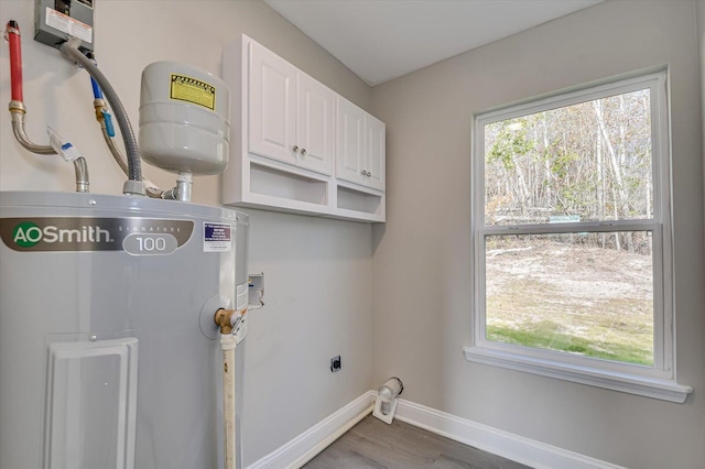 clothes washing area featuring electric water heater, dark wood-type flooring, cabinets, and hookup for an electric dryer