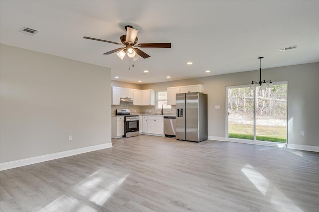 kitchen featuring a healthy amount of sunlight, pendant lighting, white cabinets, and stainless steel appliances