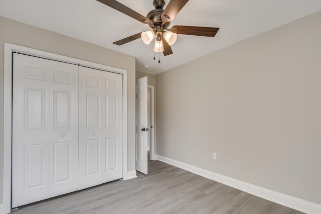 unfurnished bedroom with ceiling fan, a closet, and light wood-type flooring