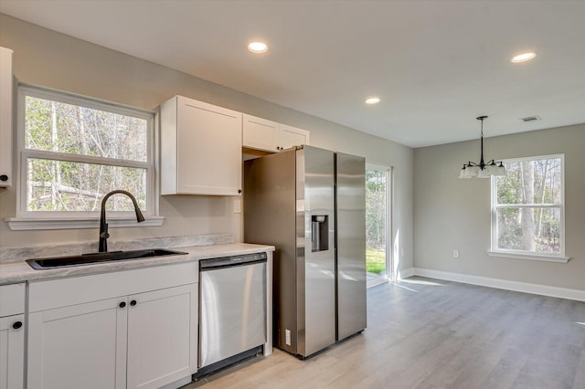 kitchen with stainless steel appliances, sink, light hardwood / wood-style flooring, white cabinets, and a chandelier