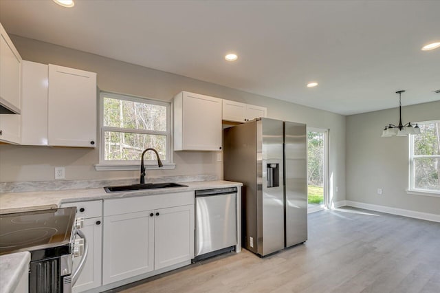 kitchen with sink, white cabinets, light hardwood / wood-style floors, and appliances with stainless steel finishes