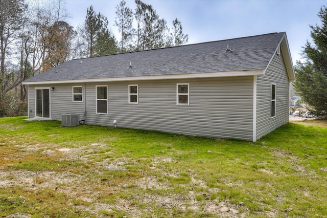 rear view of house with central air condition unit and a yard