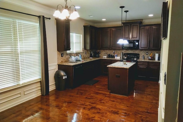 kitchen with crown molding, light stone counters, dark hardwood / wood-style flooring, pendant lighting, and a kitchen island with sink