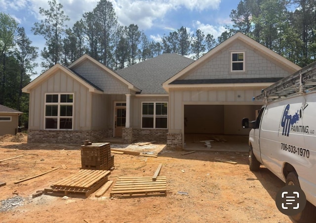view of front of house featuring an attached garage, driveway, brick siding, and roof with shingles