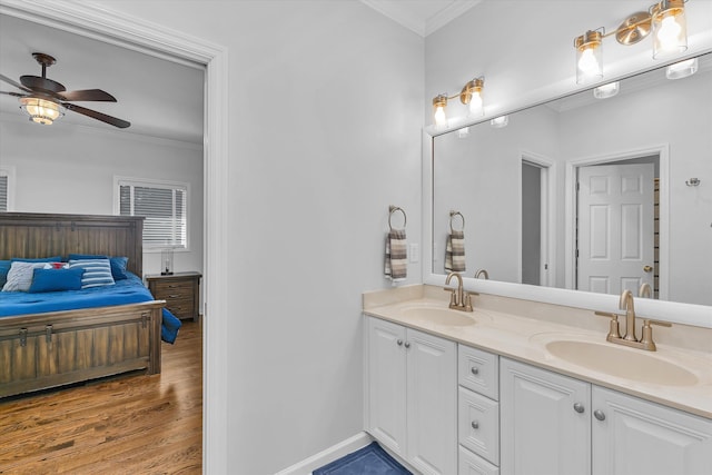 bathroom featuring ceiling fan, wood-type flooring, crown molding, and vanity