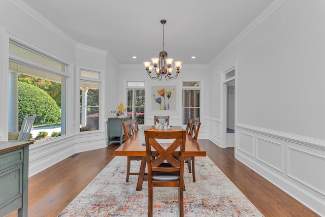 dining space with dark wood-type flooring, an inviting chandelier, and ornamental molding