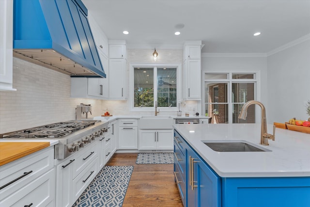 kitchen with blue cabinetry, sink, wall chimney exhaust hood, and stainless steel gas cooktop