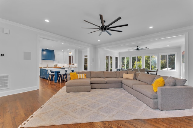 living room featuring hardwood / wood-style flooring, ceiling fan, and ornamental molding