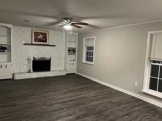 unfurnished living room with a large fireplace, dark hardwood / wood-style flooring, built in features, and ornamental molding