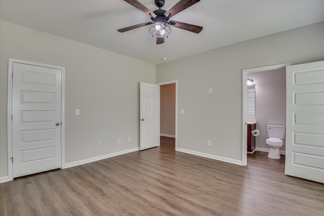 unfurnished bedroom with wood finished floors, a ceiling fan, ensuite bath, and baseboards