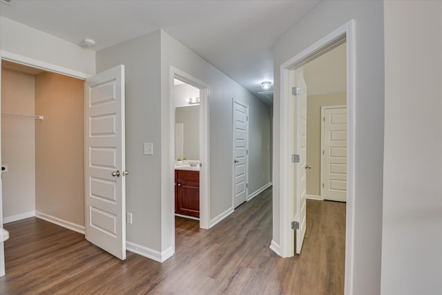 hallway with baseboards, dark wood-type flooring, and a sink