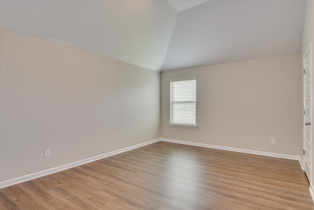 unfurnished room featuring baseboards, wood finished floors, and vaulted ceiling