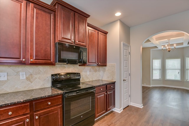 kitchen featuring tasteful backsplash, black appliances, wood finished floors, and arched walkways