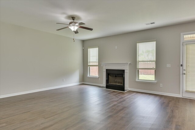unfurnished living room with dark wood-style floors, a ceiling fan, visible vents, and a wealth of natural light
