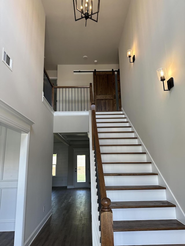 2417 Laurens St, Grovetown, GA 30813 - staircase featuring a barn door, wood finished floors, baseboards, a chandelier, and a towering ceiling