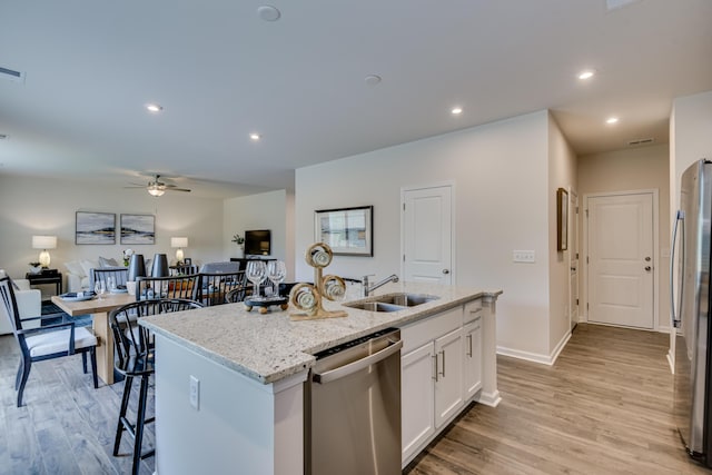 2027 Saylor Ln, Grovetown, GA 30813 - kitchen with stainless steel appliances, a kitchen island with sink, light wood finished floors, light stone countertops, and white cabinets
