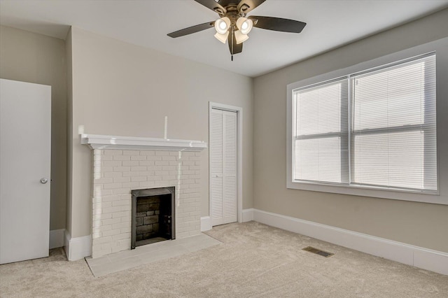 unfurnished living room featuring ceiling fan, light colored carpet, a healthy amount of sunlight, and a brick fireplace