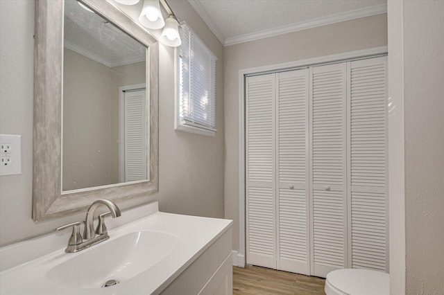 bathroom featuring hardwood / wood-style flooring, crown molding, vanity, and a textured ceiling