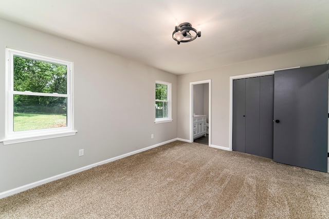 unfurnished bedroom featuring connected bathroom, a closet, and carpet floors