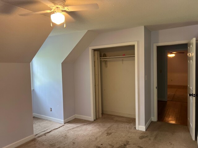 unfurnished bedroom with ceiling fan, vaulted ceiling, light colored carpet, and a closet