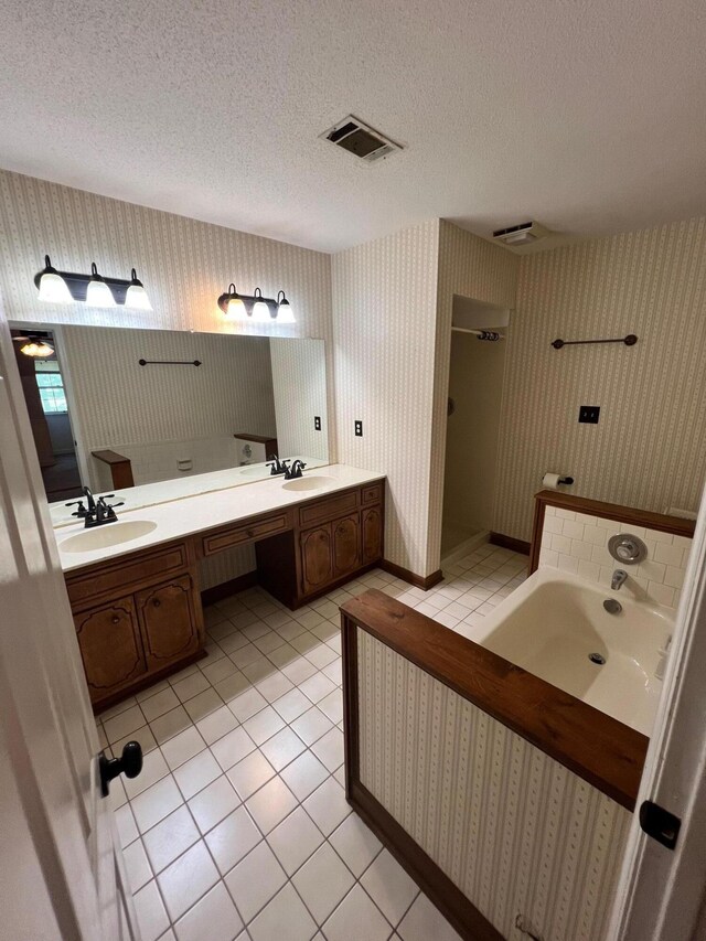 bathroom featuring vanity, a textured ceiling, a tub to relax in, and tile patterned floors