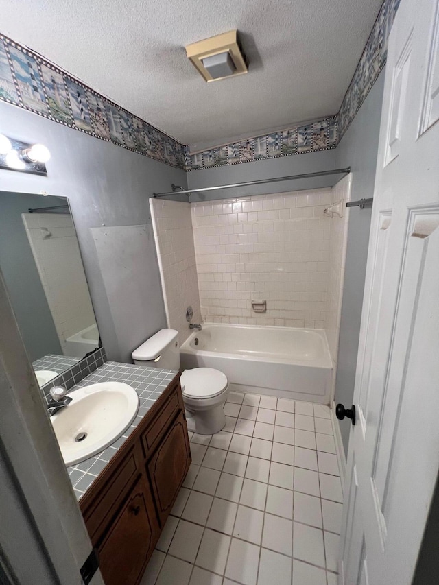 full bathroom featuring vanity, tile patterned floors, tiled shower / bath combo, toilet, and a textured ceiling