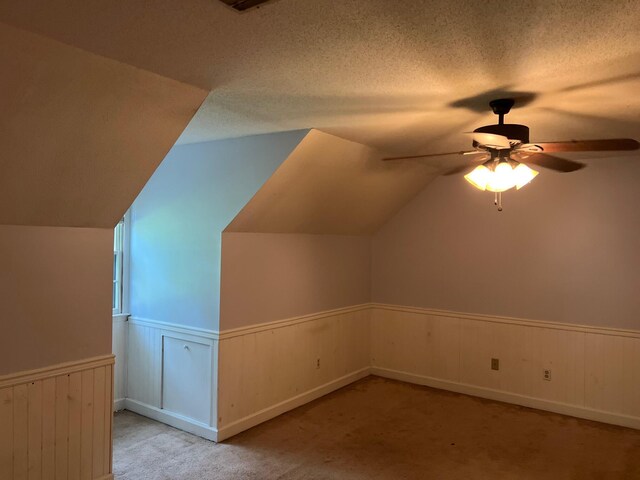 additional living space featuring a textured ceiling, light carpet, ceiling fan, and lofted ceiling