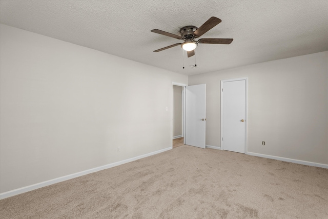 interior space with a textured ceiling, carpet flooring, baseboards, and a ceiling fan