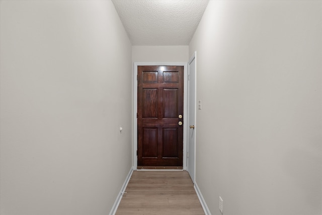 entryway featuring light wood-style floors, a textured ceiling, and baseboards