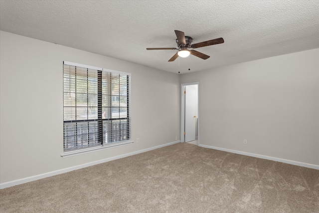 carpeted spare room featuring a textured ceiling, ceiling fan, and baseboards