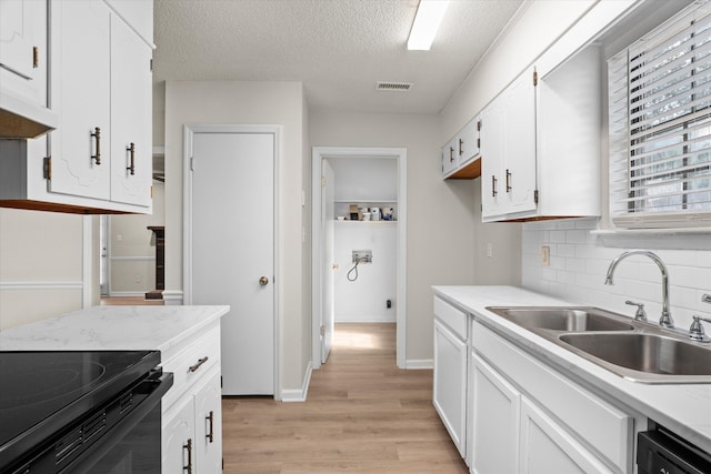kitchen with dishwasher, a sink, light countertops, white cabinetry, and light wood-style flooring