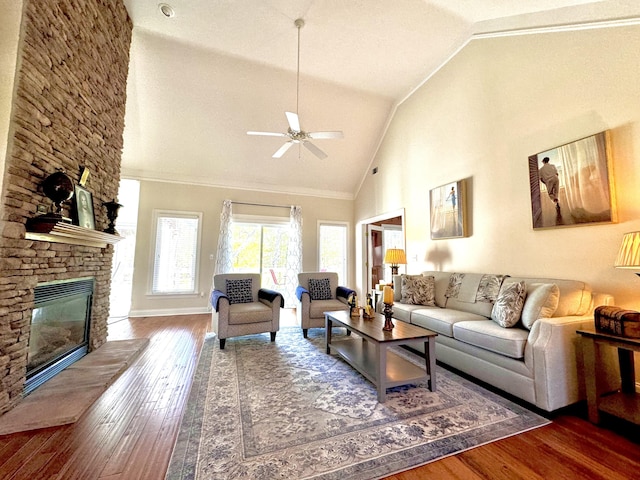 living room featuring ceiling fan, dark wood-type flooring, a stone fireplace, lofted ceiling, and ornamental molding