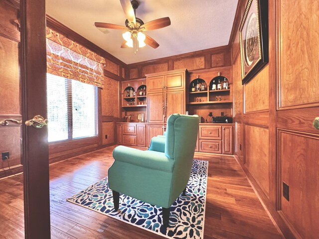 home office featuring dark wood-type flooring, built in features, crown molding, and wood walls