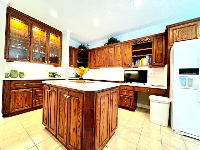 kitchen featuring white refrigerator with ice dispenser, light tile patterned floors, a kitchen island, and ornamental molding