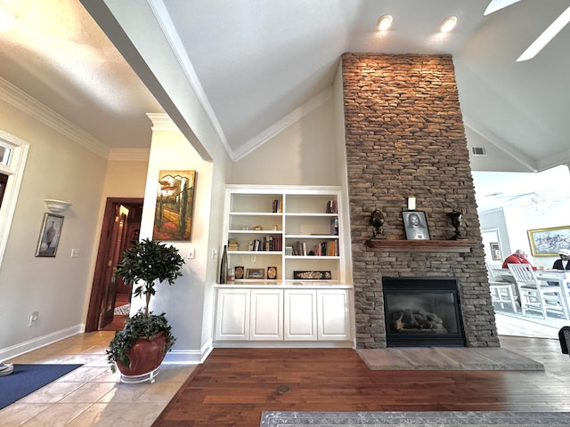 living room with lofted ceiling, crown molding, hardwood / wood-style flooring, ceiling fan, and a fireplace